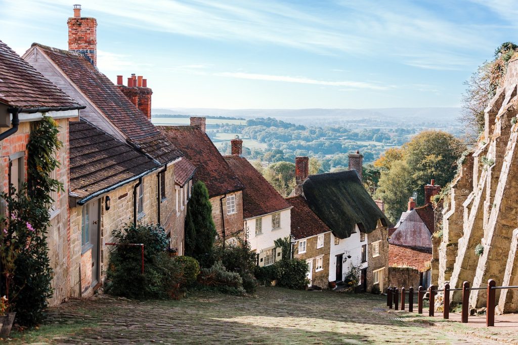 Quaint English village with cobblestone street, traditional cottages and scenic countryside view