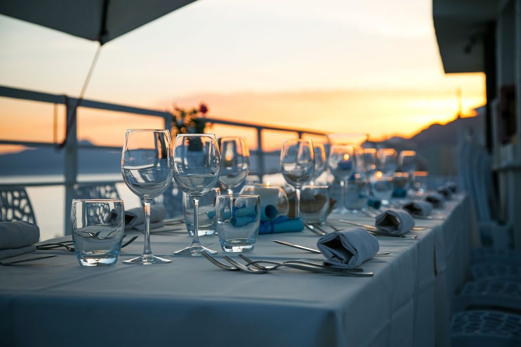 Elegant outdoor dining setup with wine glasses at sunset overlooking a scenic balcony view