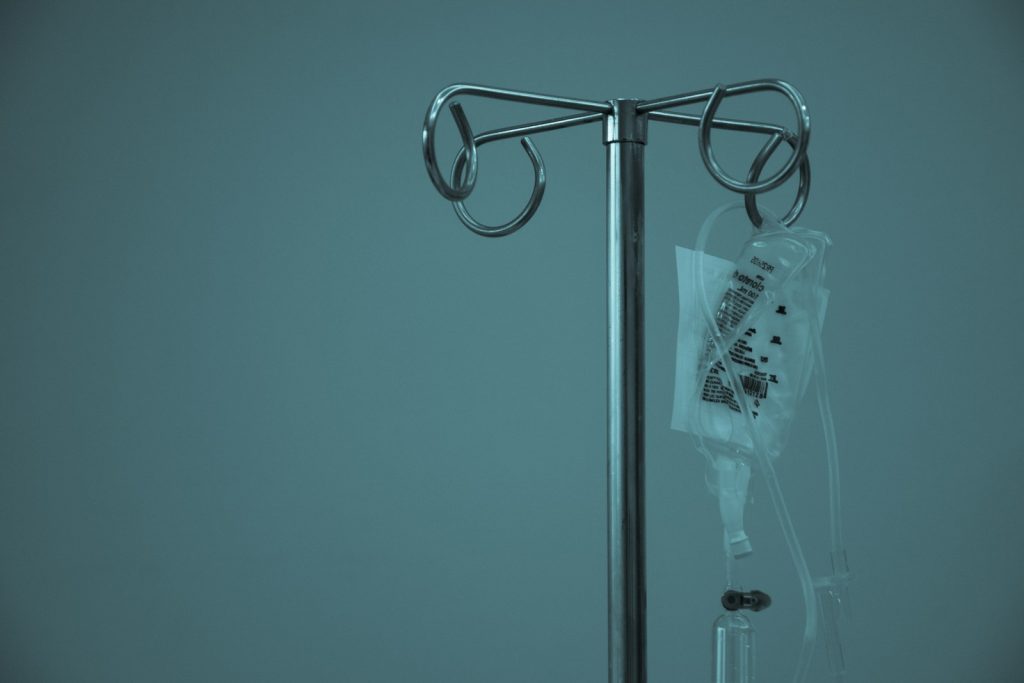 IV drip bag hanging on metal stand in hospital setting, symbolising medical treatment and recovery