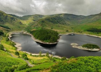 Idyllic mountain scenery with a serene lake and lush greenery under cloudy skies, perfect for nature lovers and hikers