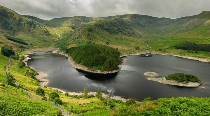 Idyllic mountain scenery with a serene lake and lush greenery under cloudy skies, perfect for nature lovers and hikers