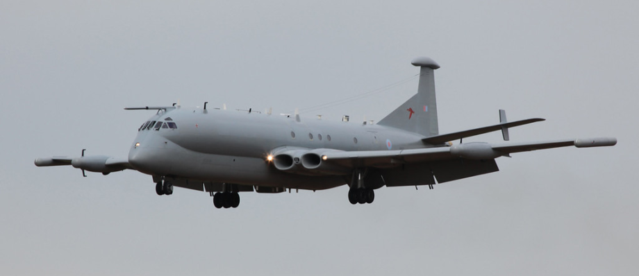 Grey military aircraft in mid-air flight against a cloudy sky background