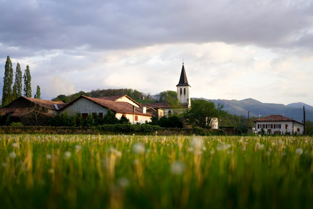 Scenic rural village with church steeple and traditional houses in lush countryside landscape at dusk