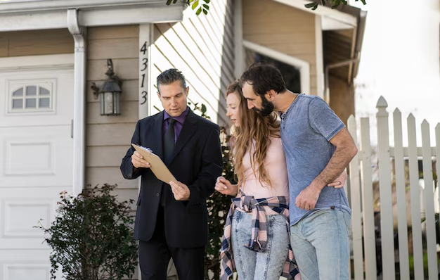 Real estate agent showing a couple a house listing outside a modern home