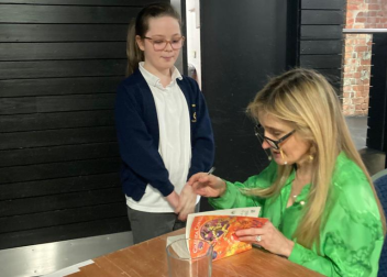 Author signing a book for a young fan at an event, showcasing creativity and inspiration in literature