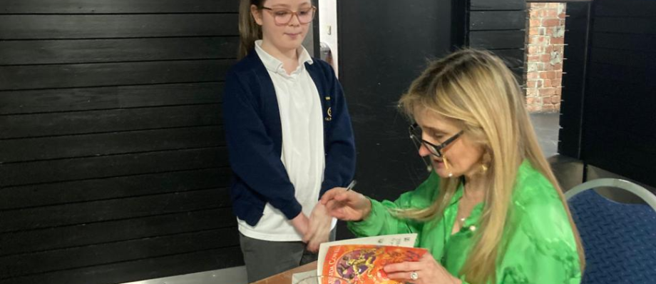 Author signing a book for a young fan at an event, showcasing creativity and inspiration in literature