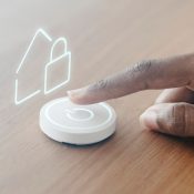 A hand activating a button with a house symbol, representing home-related functions or services