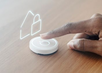 A hand activating a button with a house symbol, representing home-related functions or services