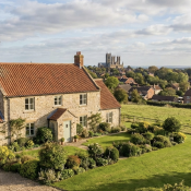Idyllic country house with red roof, lush garden and distant village view in sunny rural England landscape Waddington