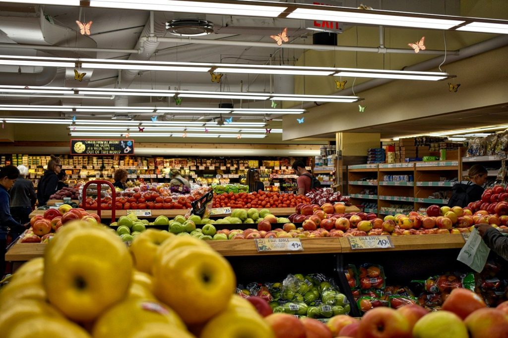 Shoppers browsing fresh produce at a well-stocked supermarket fruit and vegetable section