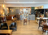 Cosy coffee shop interior with wooden tables, chairs, and leather sofas, warm lighting enhancing the inviting atmosphere