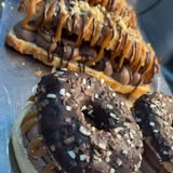 Assorted chocolate-topped pastries including a doughnut and waffles, drizzled with caramel and sprinkled with nuts