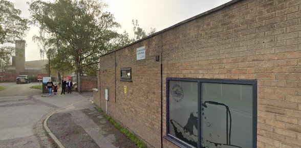 Brick building exterior with people in the distance near a tree on a cloudy day in an urban environment