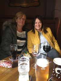 Two women sitting in a pub enjoying drinks with a variety of beverages on a wooden table