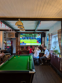 People watching sports on TV in a cosy pub with a pool table nearby