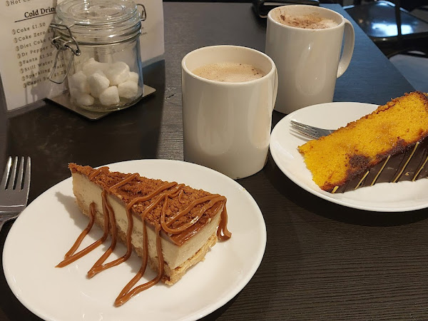 Cheesecake and sponge cake with two cups of coffee on a cafe table setting