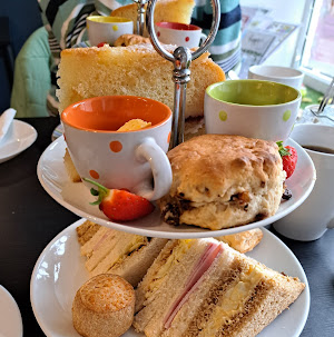 Afternoon tea set with assorted sandwiches, scones, and cakes on a tiered stand, perfect for a cosy British tea time