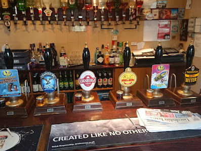 Traditional British pub bar with various beer taps and bottles displayed behind the counter