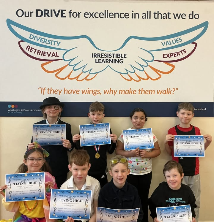 Students proudly display Flying High certificates at Waddington All Saints Academy under motivational wing-themed poster