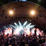 Vibrant live music performance at an outdoor festival with enthusiastic crowd.