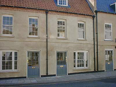 Row of charming terraced houses with blue doors and traditional architecture in a quaint UK village setting