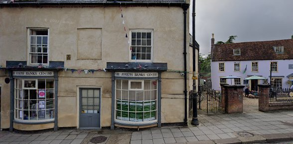 Historic building housing Sir Joseph Banks Centre, with bunting and neighbouring structures, located on a cobblestone street