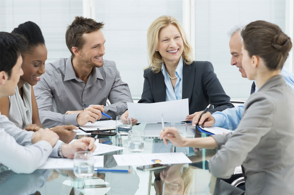 Business team in a meeting room, collaborating on a project with documents and laptops on a glass table