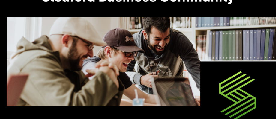 Men laughing around a laptop, promoting collaboration in the Sleaford Business Community meeting space
