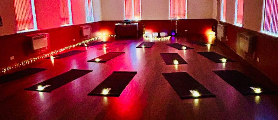Dimly lit yoga studio with mats laid out, illuminated by soft red and purple lighting ideal for a calming session