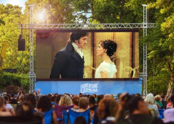 Outdoor cinema showing romantic film to a crowd in a park setting