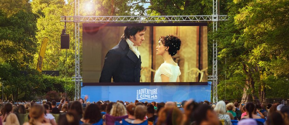 Outdoor cinema showing romantic film to a crowd in a park setting