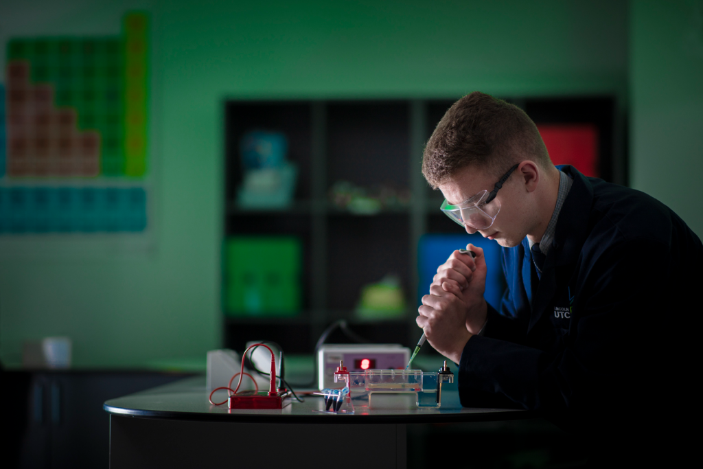 Student conducting science experiment in laboratory with safety goggles, pipette, and modern equipment on the table