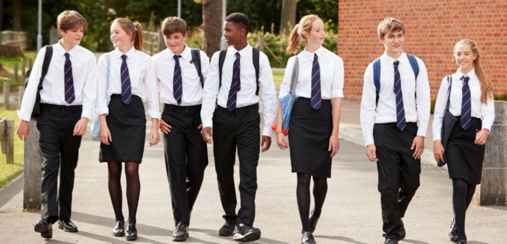 Group of school students in uniform walking outdoors with backpacks