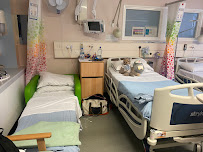 Hospital room with hospital bed, medical equipment, colourful curtains, and adjacent visitor sleeping area
