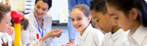 Children in a classroom engaged in a science experiment with guidance from their teacher