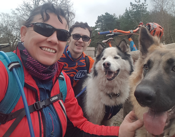 Group of people with two happy dogs on a biking adventure in a forest setting