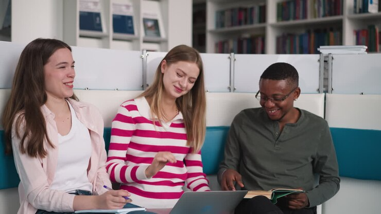 Diverse students studying together in a library, using a laptop and enjoying collaborative learning experiences