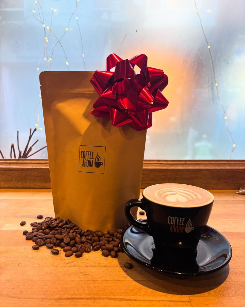 Coffee Aroma gift bag with coffee beans and a cappuccino in a black cup on a wooden table, festive presentation