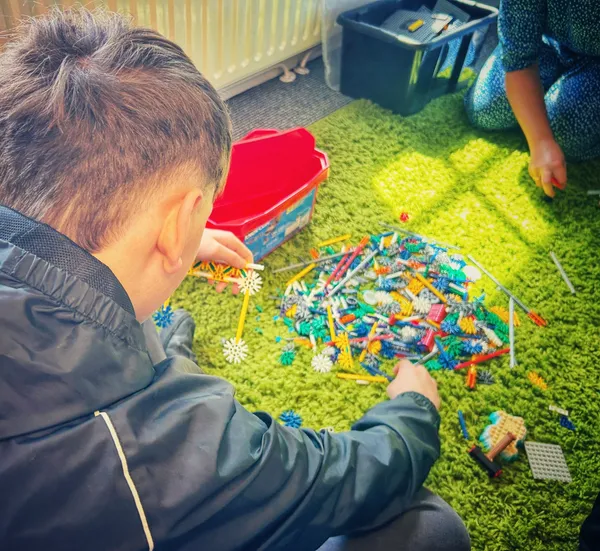 Child building with colourful construction toys on a green carpet, enhancing creativity and motor skills