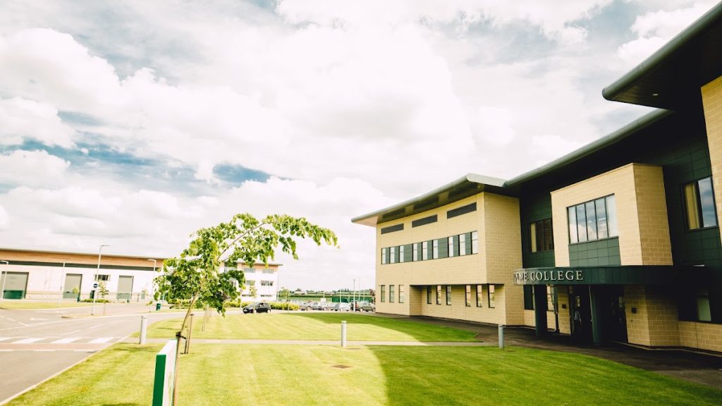 Modern college building with green lawn under a cloudy sky, showcasing contemporary educational architecture