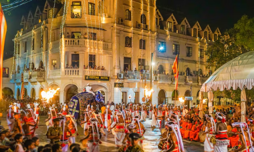 Vibrant cultural procession with dancers in traditional attire and an elaborately decorated elephant at night festival