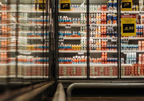Supermarket aisle with shelves stocked with diverse yoghurt brands and vibrant packaging in a well-lit refrigerated section